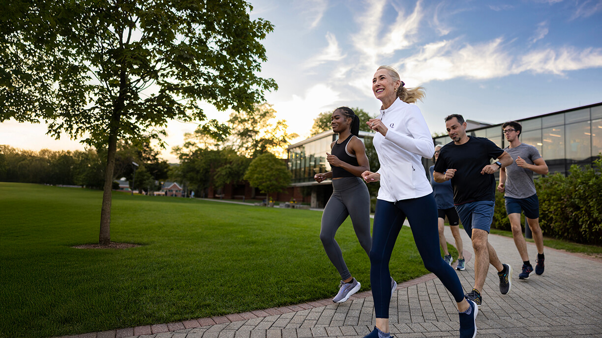 Quinnipiac University's 10th president, Marie Hardin, running on campus with students and faculty