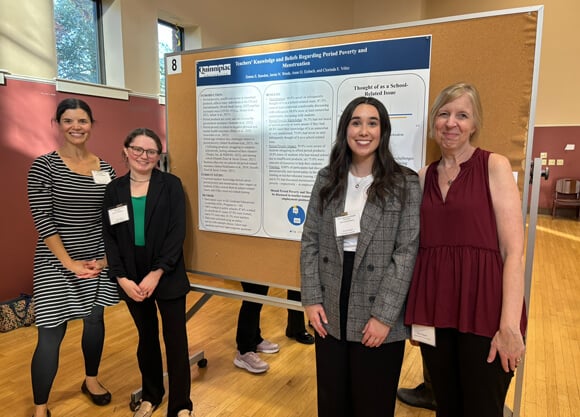Students and professors stand in front of poster