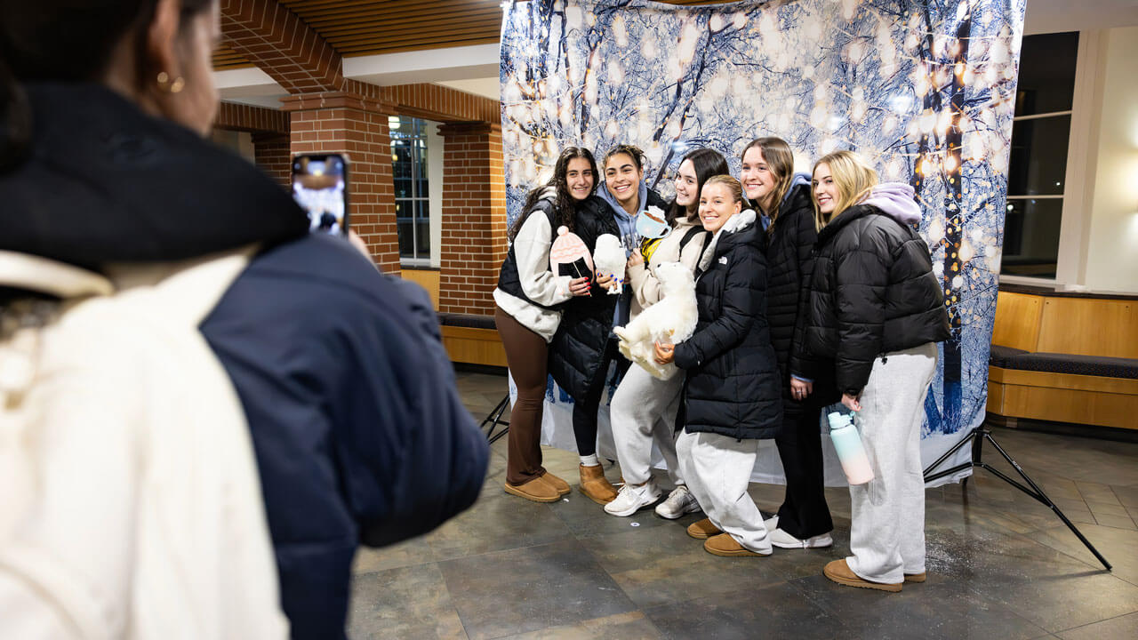 Group of students holding stuff animals and holiday decorations for a photo