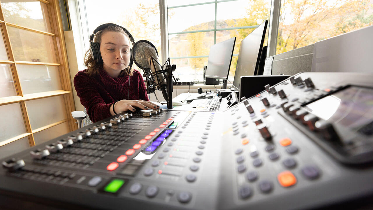 Student at the sound board in the School of Communications Podcast Studio