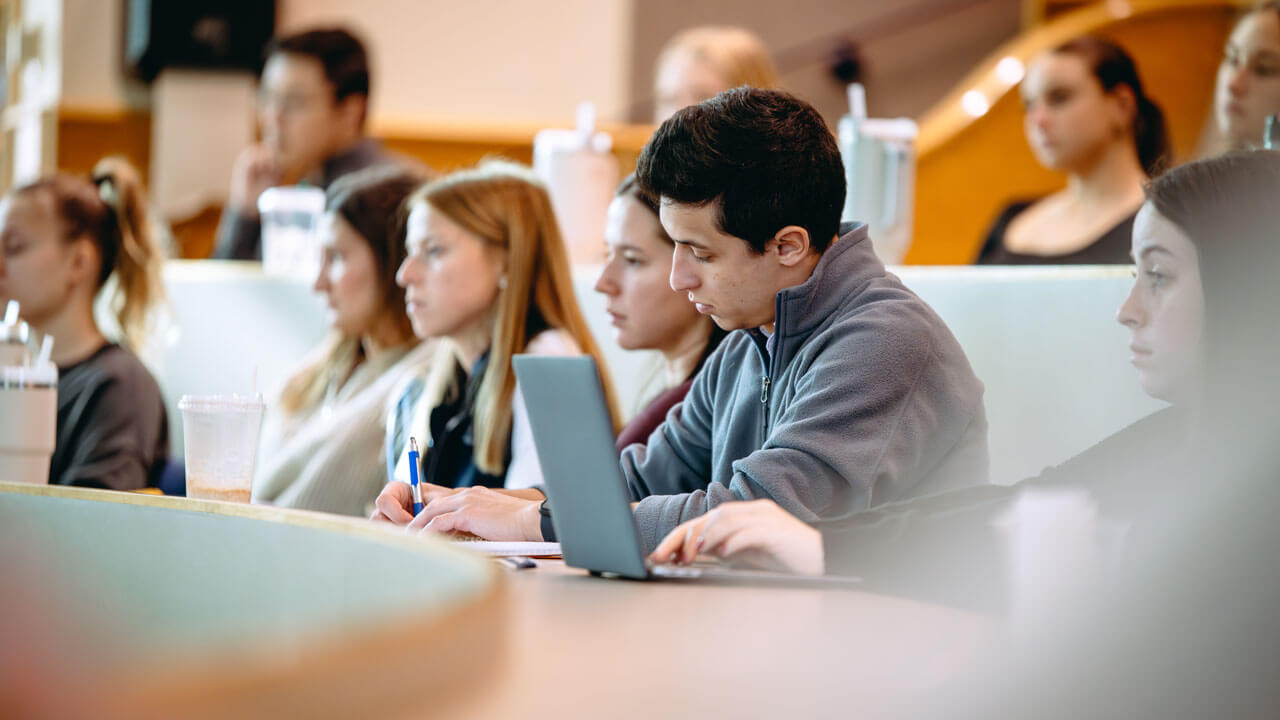 Students take notes on their computers and notebooks.