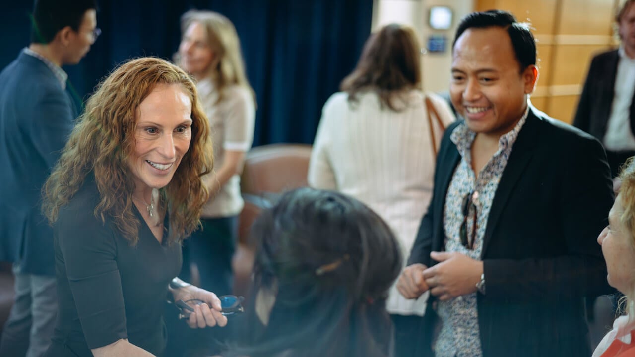 A panelist shakes hand with another person smiling.