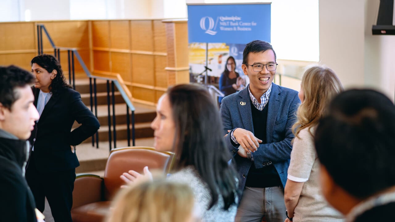 A group of professionals are gathered, talking and smiling.