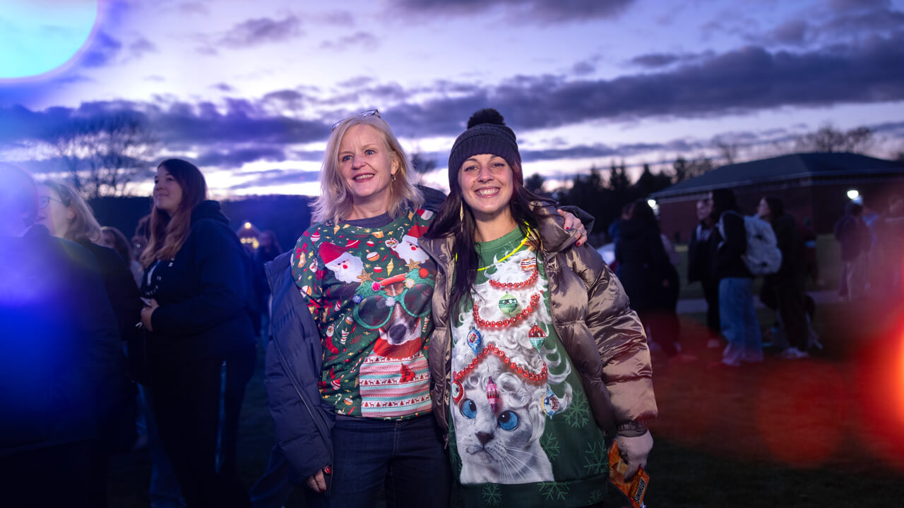 People pose for a photo with holiday lights