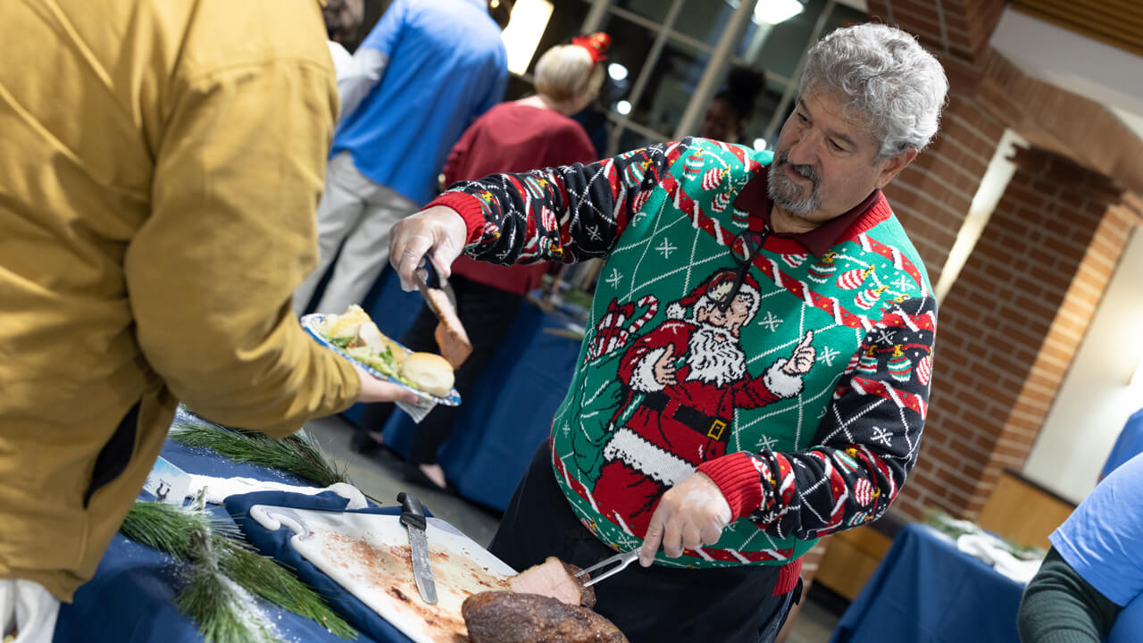 A person serving food in a holiday sweater