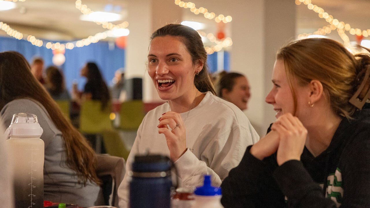 Students laugh and converse with each other at a table