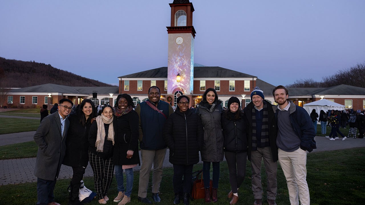 Students faculty and staff smiling in front of the Arnold Bernhard Library