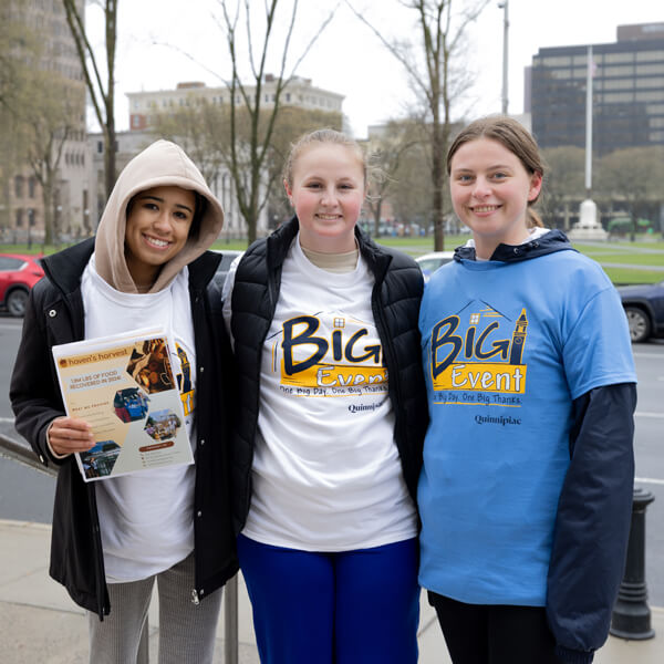 Three students stand arm-in-arm in downtown New Haven during Big Event