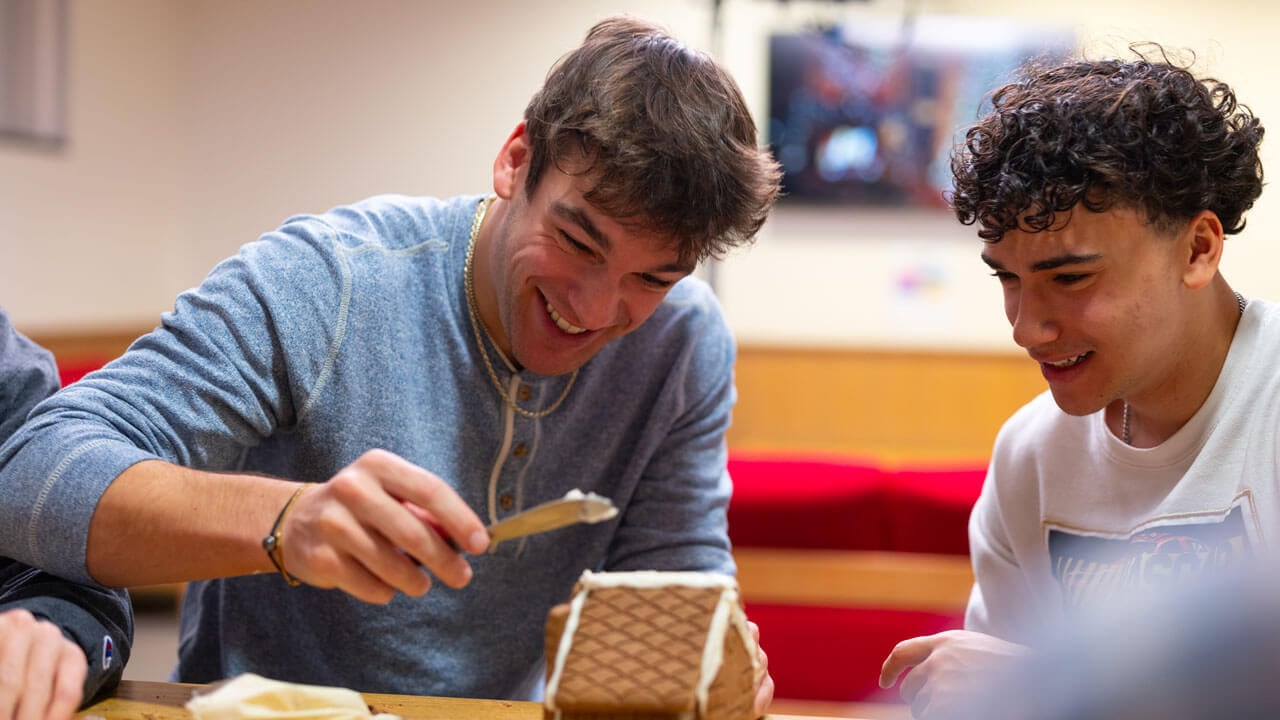 Two students create a gingerbread house together