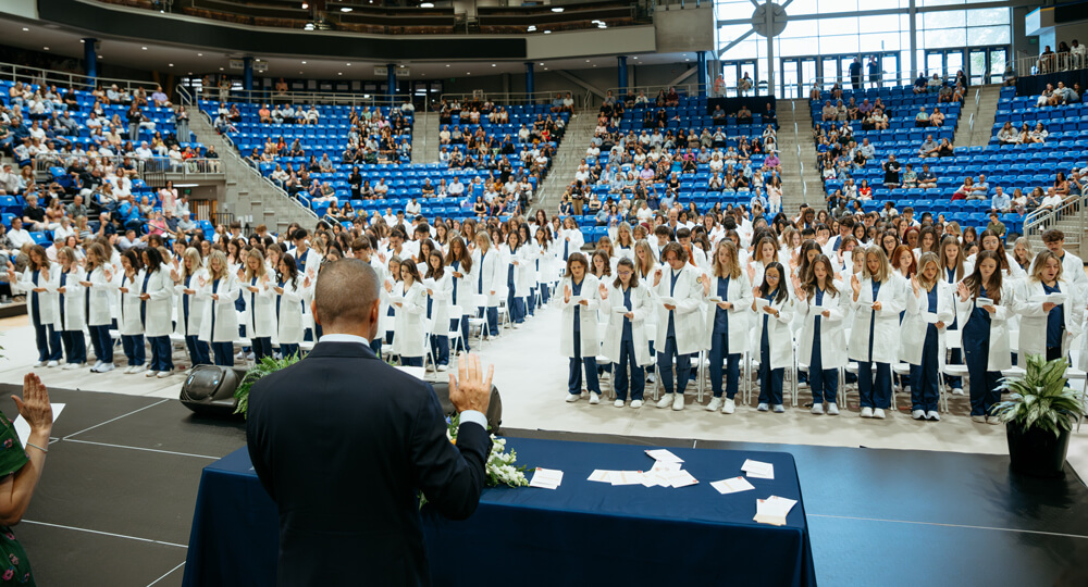 A class of nursing students taking an oath at a white coat ceremony