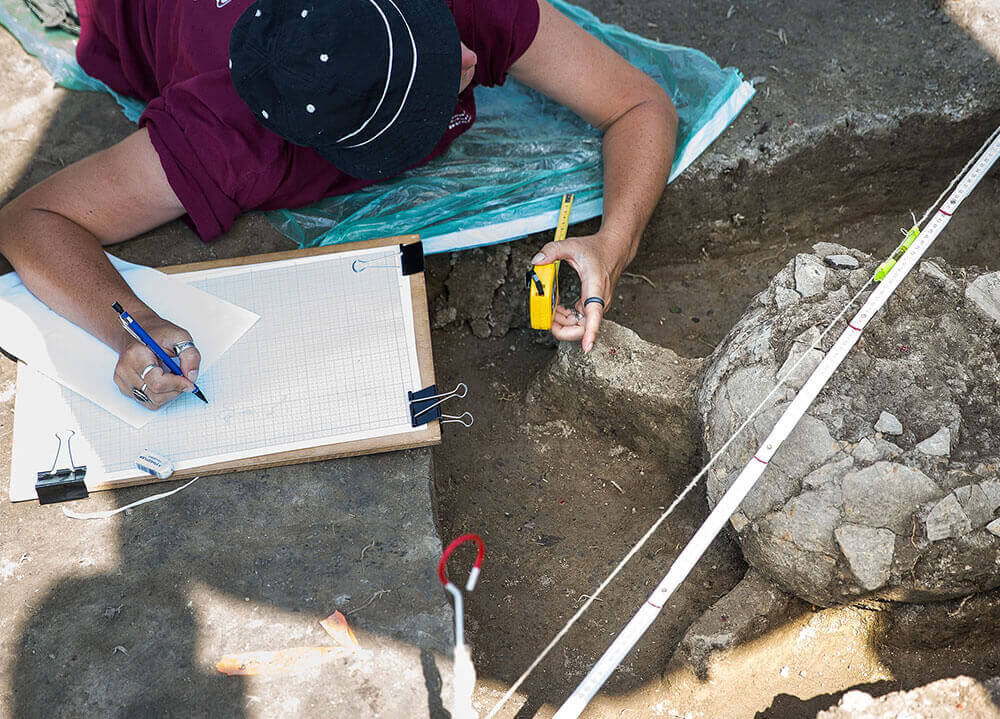 An anthropology student plots and measures the site of a dig while working in Hungary