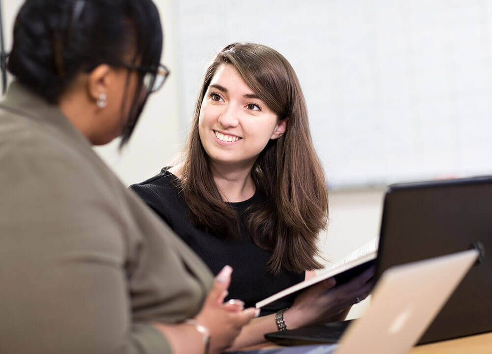 Two law students sit side-by-side as they work on an issue of a law journal