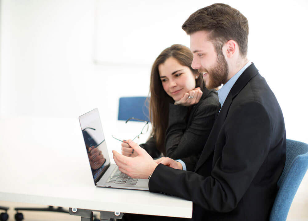 Two students work together on a laptop