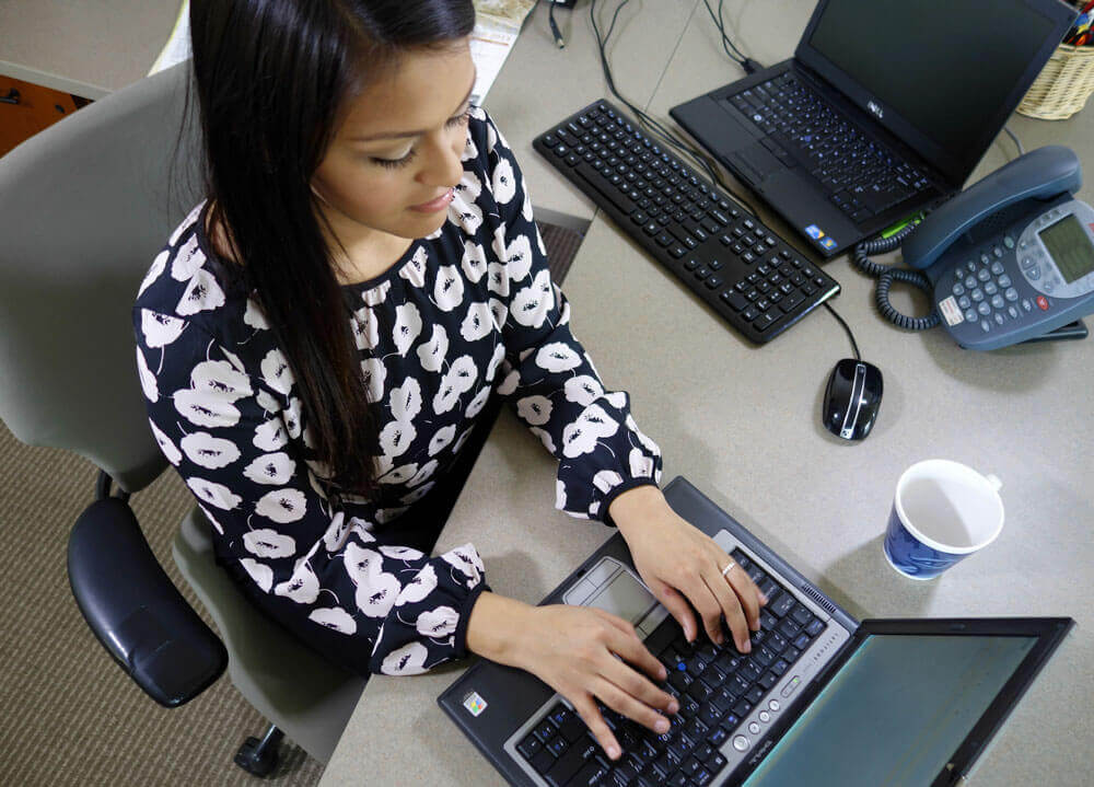 A student works on a laptop while sitting at a desk