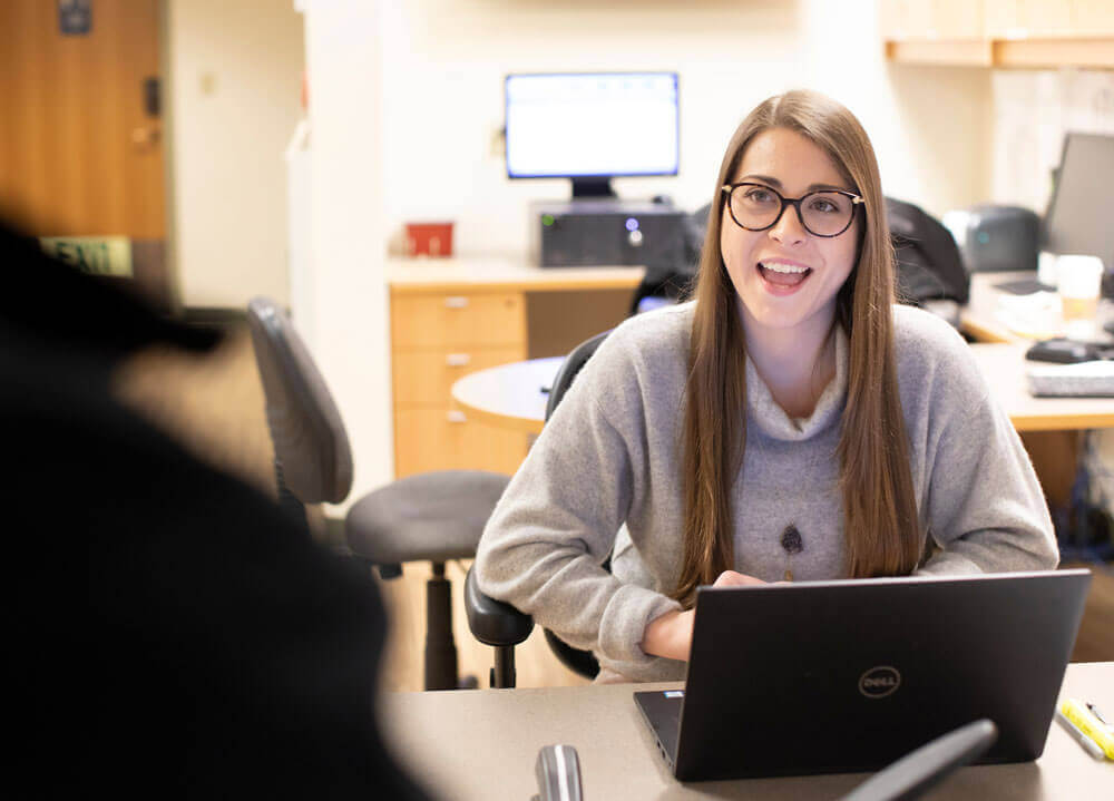 Student smiles while working on a laptop