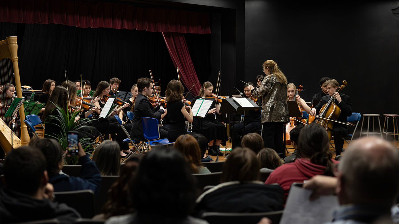 A wide photo of the stage in Buckman Theater as a group of musicians performs.