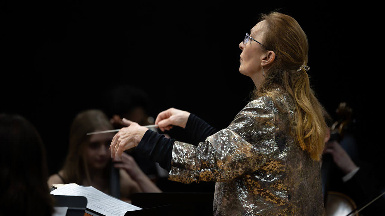 A conductor motions their students to continue playing during their winter concert.