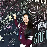 Linda Vilay writes a message in chalk on a large blackboard