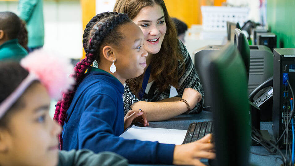 A School of Education student assists an elementary schooler with computer work