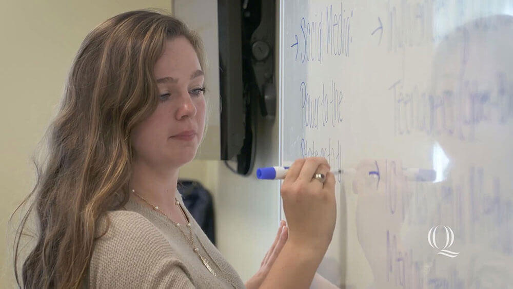 Taylor Chelo writing on a white board, starts video