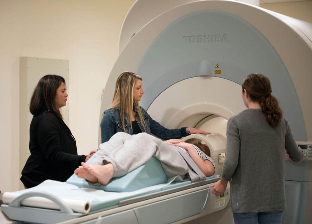 Students get ready to perform an abdominal scan on a volunteer as the professor watches