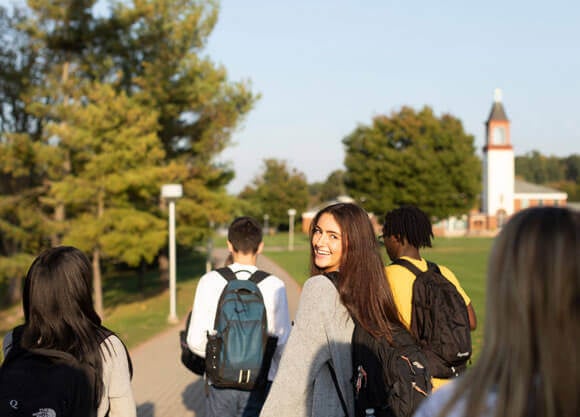 Half a dozen students walk across the quad in front of the library