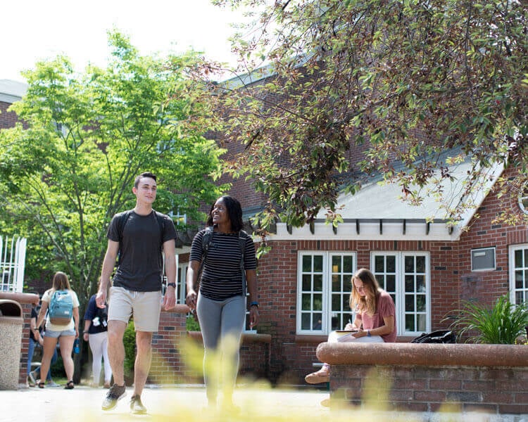 Two students talk as they walk by residence halls.