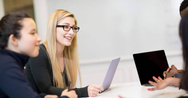 Three students with laptops in class