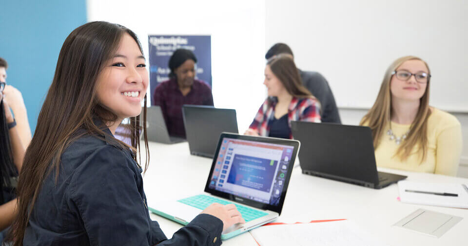 Student uses a laptop in a business classroom