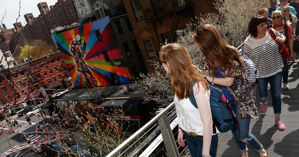 Several students on the New York high line look at a colorful mural in the distance