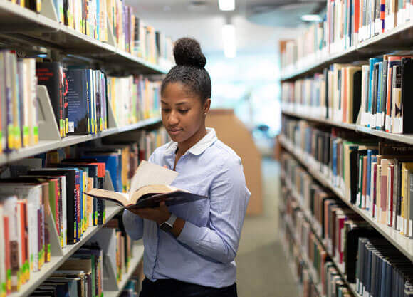 An orientation leader reads in the library.