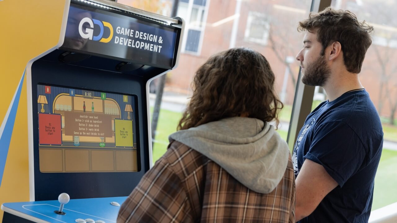 Two people playing a game on a Quinnipiac Game Design and Development arcade cabinet