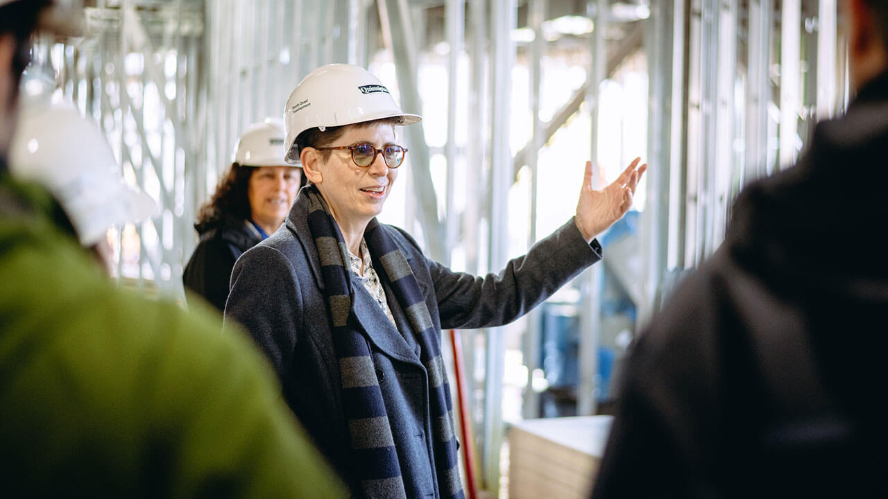 Debra Liebowitz points her finger forward speaking with QU staff in a South Quad building.