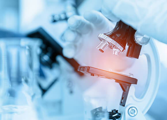 A close-up shot of a scientist using microscope in lab.