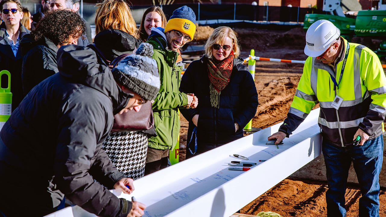 Jamie and Becky watching staff members signing the South Quad beam.