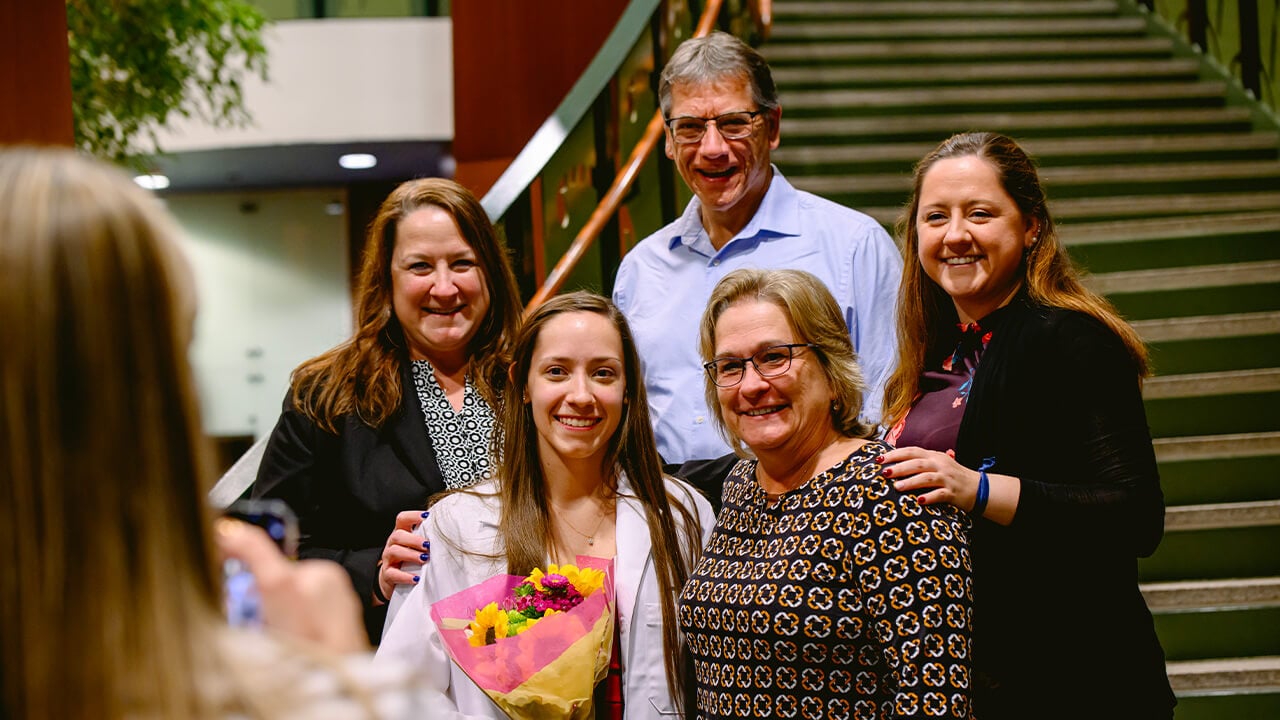 5 individuals in a family stand on stairs to smile for a photo.