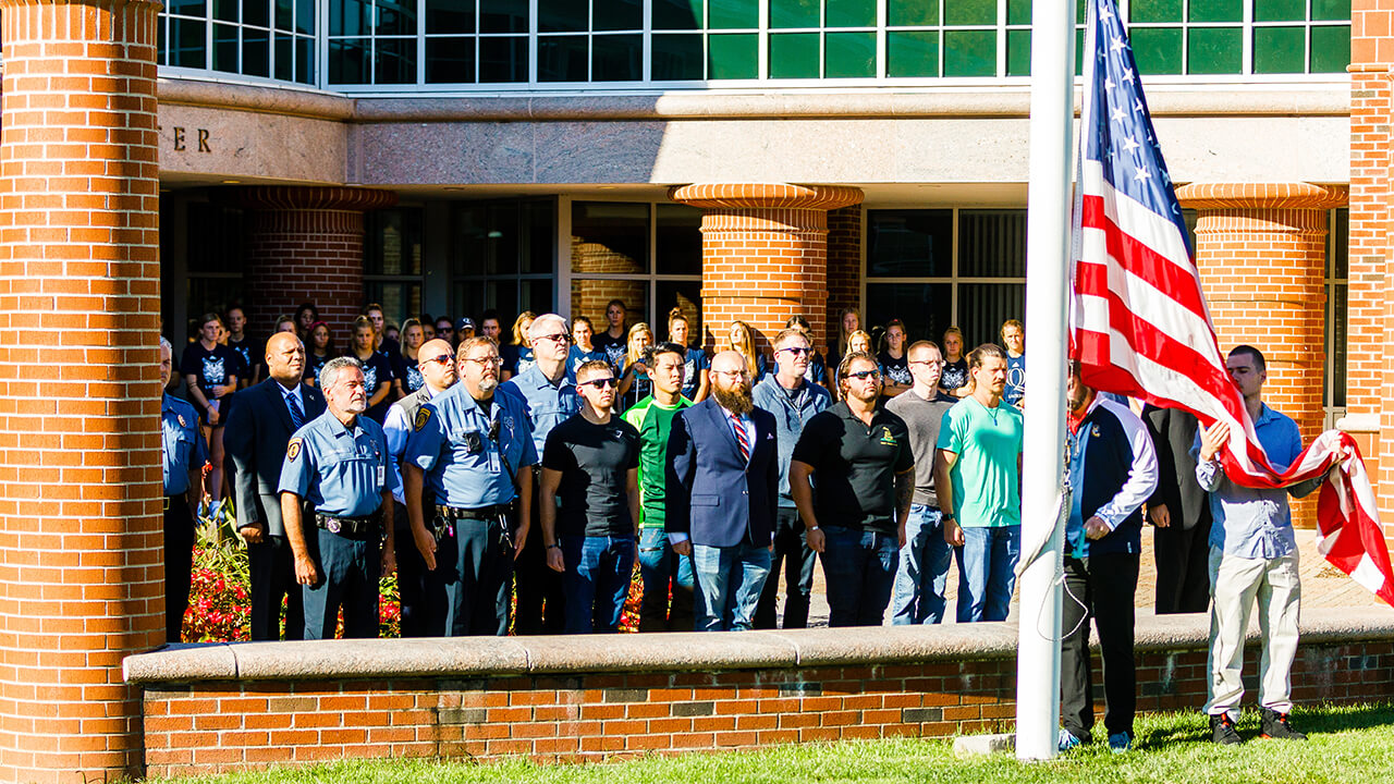 Members of the community pause during the flag-raising ceremony.