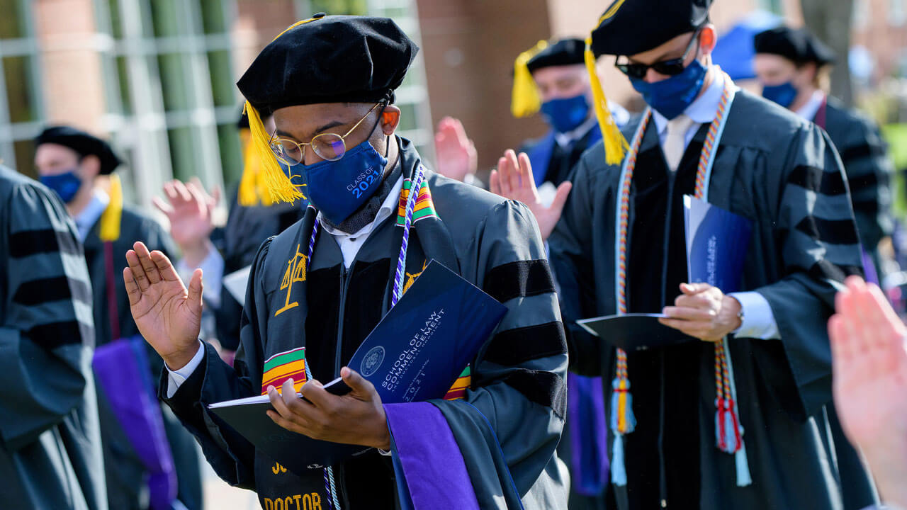 Several graduates raise their hands as they recite an oath