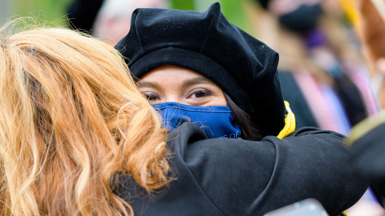 A graduate embraces her family member