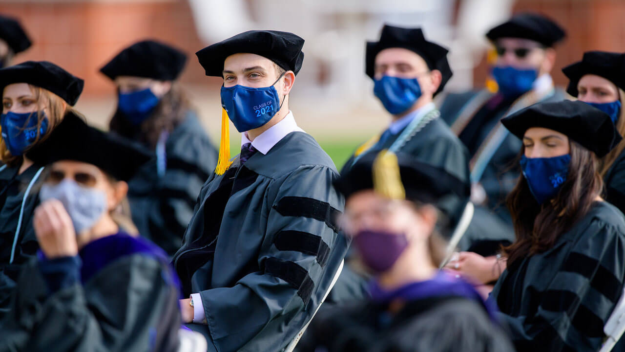 Graduates listen to the speakers as they sit in their seats on the quad