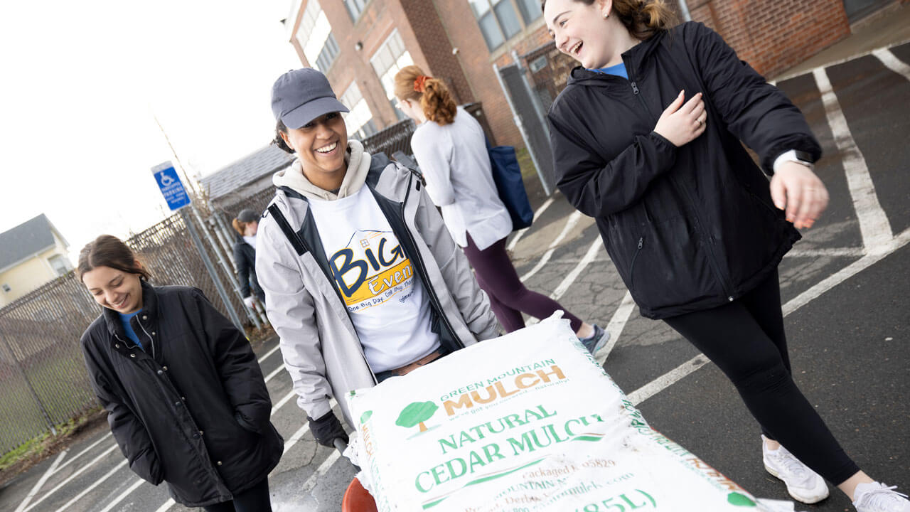 Students wheel bag of mulch to help at the Big Event