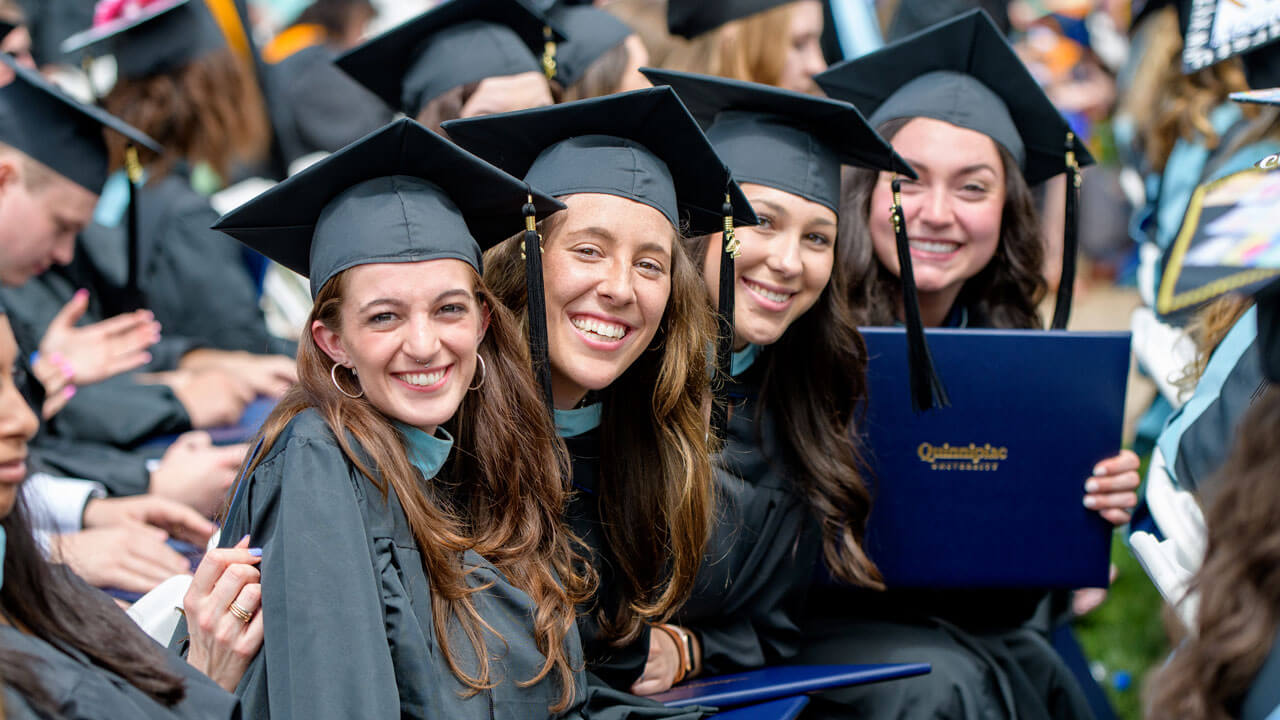 Group of graduate students take a photo together while sitting at the graduate ceremony