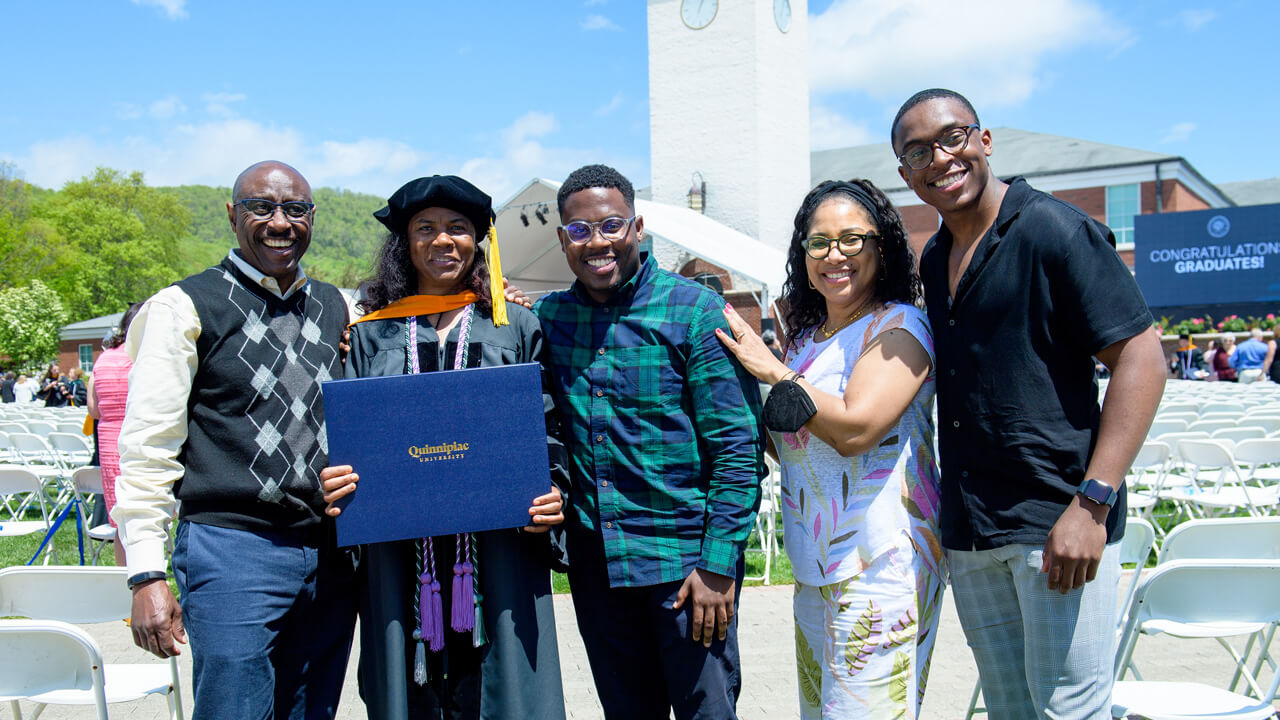 A graduate and their family standing for a photo outside the Arnold Bernhard Library.