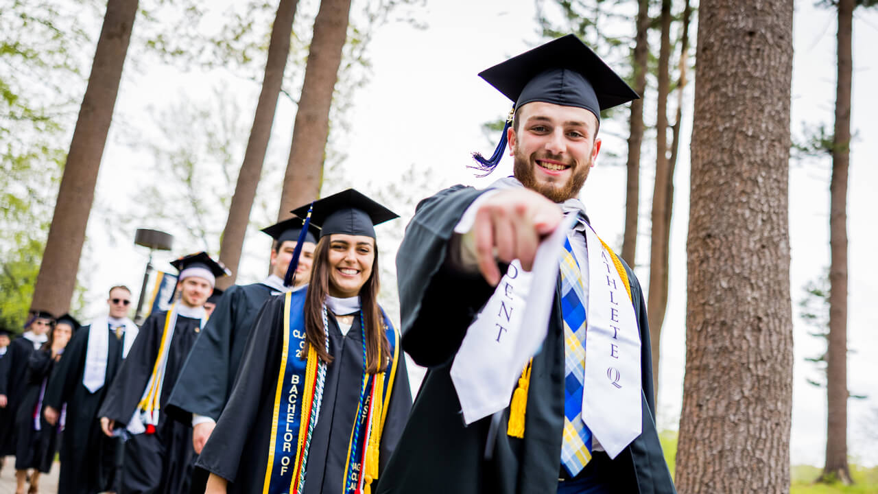 Graduate student points at the camera with a smile