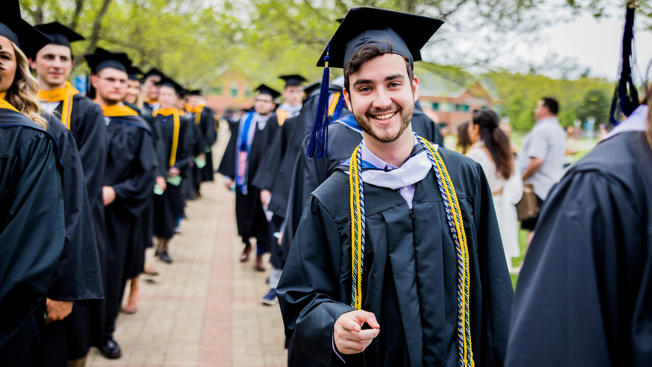 Graduate points at the camera in line with his peers