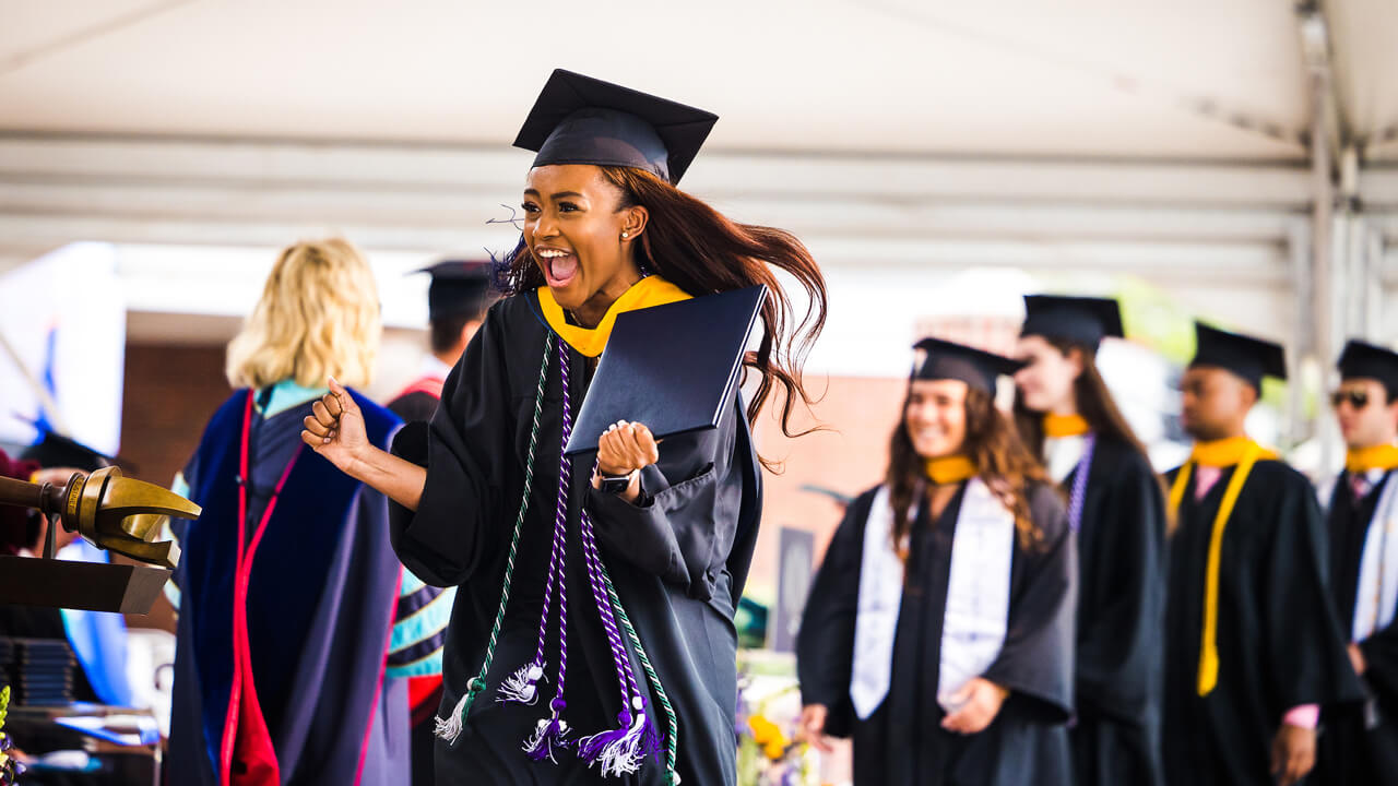 A graduate cheers as she crosses the Commencement stage