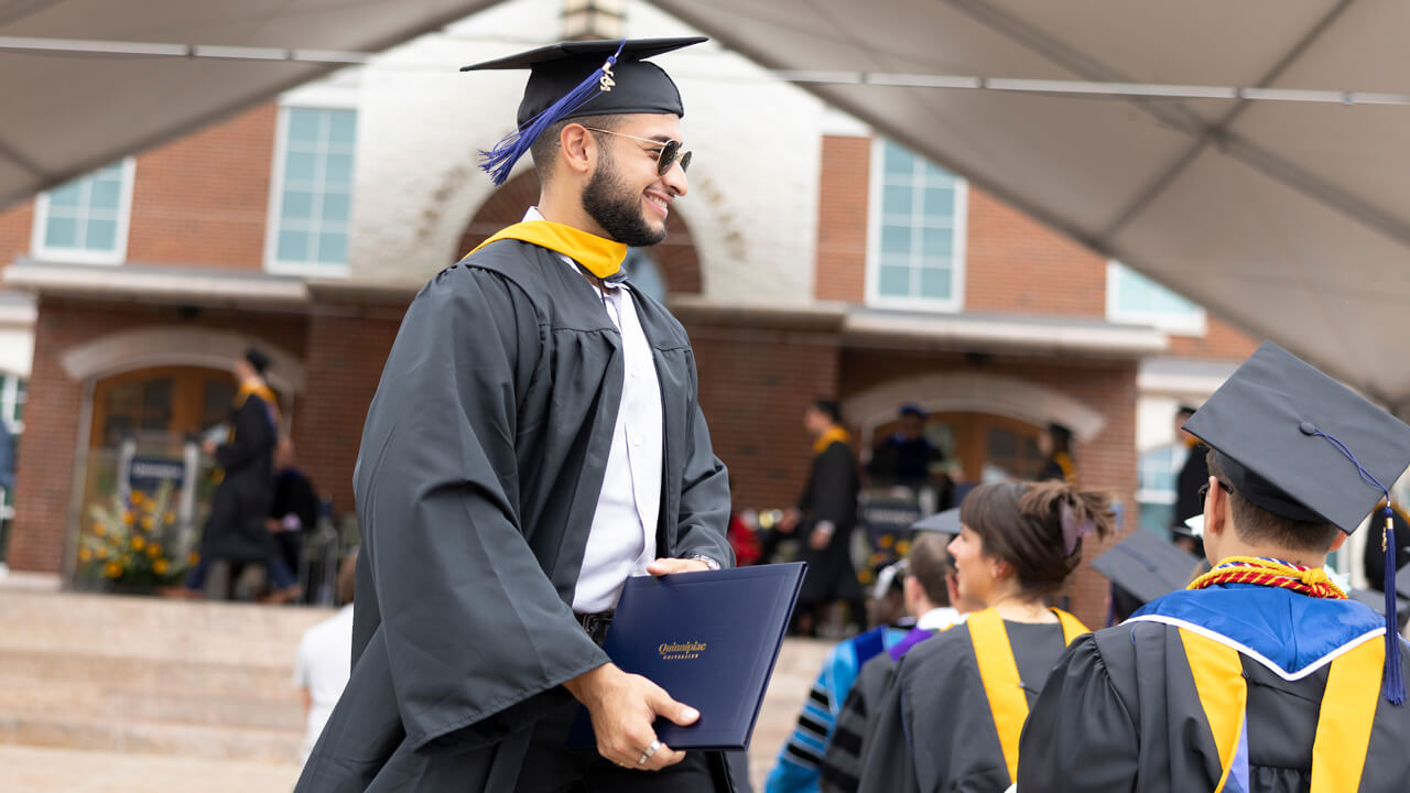 Graduate walks back to his seat with his diploma in hand