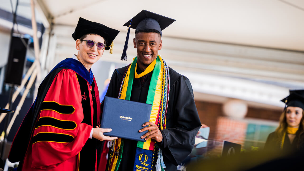 Provost Deb Leibowitz hands a graduate his diploma cover