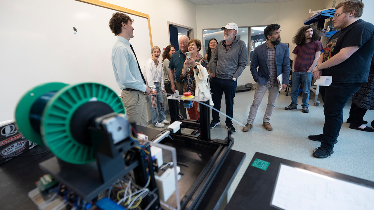 A student demonstrates their project in front of a group of people