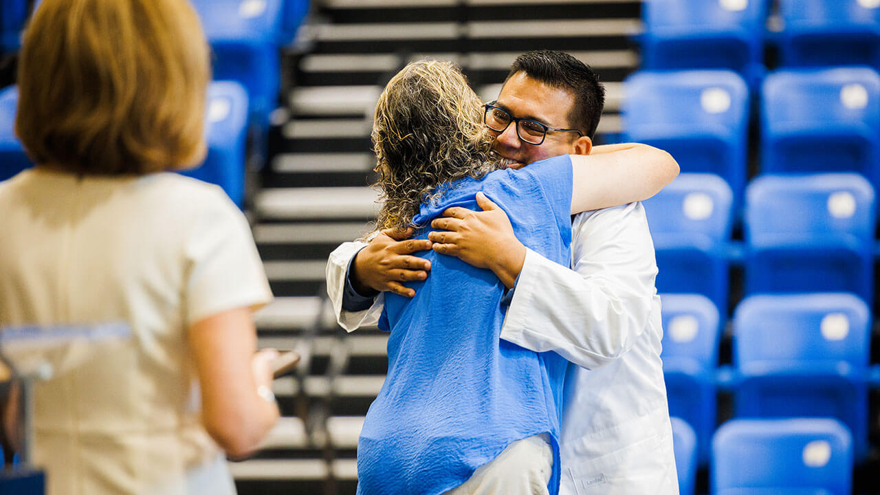 Graduate hugs faculty member on stage